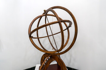 Antique brass armillary sphere on a wooden stand on white background. ancient scheme of the...