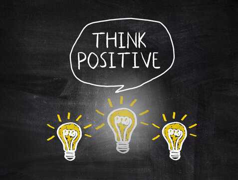 Think positive text and light bulbs on blackboard.