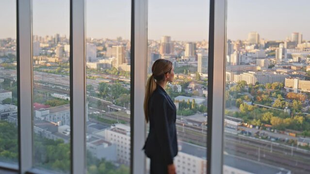 Woman leader thinking future looking panoramic window in contemporary office.