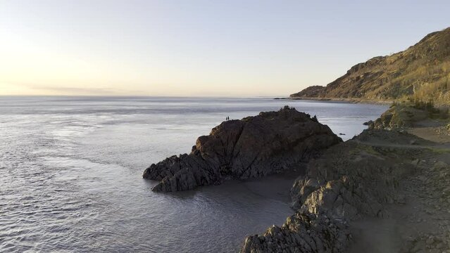 Aerial drone footage of Beluga Point Lookout along Seward Highway between Anchorage and Seward, Alaska at sunset with rocky outcrop sticking out into the Turnagain Arm inlet