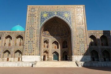 Fototapeta na wymiar Uzbek religious architecture in facade of ancient Tilya-Kori madrasah with colorful ornament on brick walls
