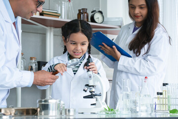 Asian scientist kid student and Indian teacher with plant at biology class in school laboratory, learning, teaching, holding magnifying glass, using microscope. Education, science and school concept