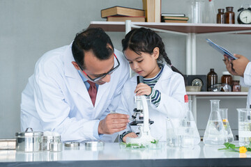Asian scientist kid student and Indian teacher with plant at biology class in school laboratory, do...