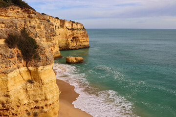 Fototapeta na wymiar Cliff around sandy beach and ocean on a winter day in southern Portugal.