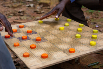 Ugandan men playing draughts (checkers) with plastic bottle lids serving as pieces. - obrazy, fototapety, plakaty