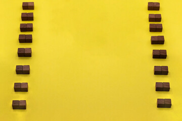 立体的な茶色のウッドキューブが縦に並んだ黄色い背景のフレーム素材