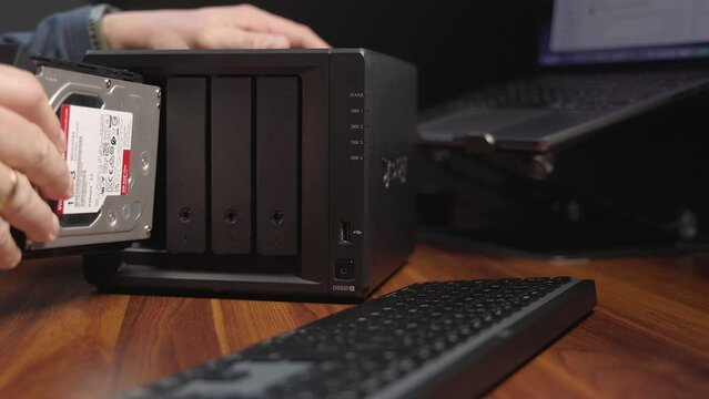 Person inserting a hard-drive into a computer server. Close-up, dolly movement