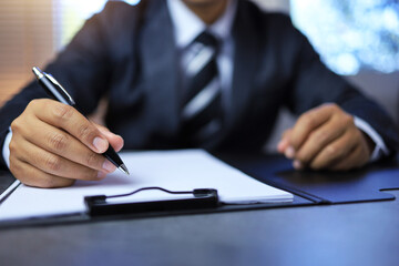 Management concept with businessman writing a pen on clipboard to approve or sign document on paper...