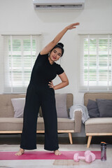 Overweight Asian woman exercising at home on a fitness mat. Beautiful Caucasian woman in casual clothes Preparing to do yoga Practice exercise in the living room