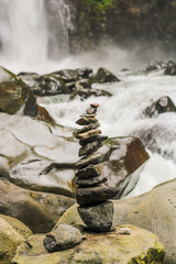 Balancing a pile of rocks with a waterfall in the background