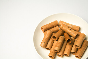 Crispy egg roll or crispy golden curl placed in a white plate, white background. Isolated.