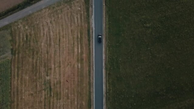 A tracking shot of a car driving through agricultural land