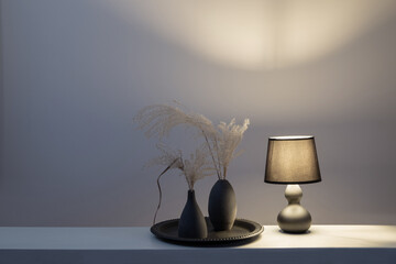 lamp with dried flowers in black vases on white shelf