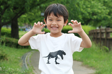 恐竜のTシャツを着て恐竜のポーズをする笑顔の男の子