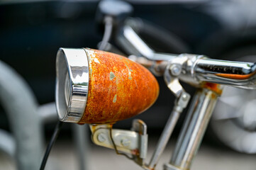 Heavily rusted bicycle light shines a beautiful rusty red, old rusty bicycle lamp, detail shot