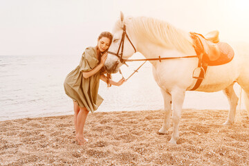 A woman in a dress stands next to a white horse on a beach, with the blue sky and sea in the background.