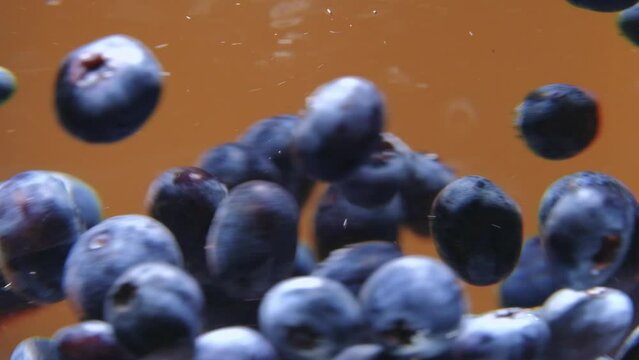 Plump blueberries are swirling in water on a brown background. Blueberries contain a lot of anthocyanins, which can support collagen synthesis. Fresh fruit concept.
