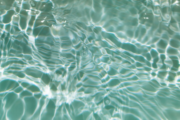Bluewater waves on the surface ripples blurred. Defocus blurred transparent blue colored clear calm water surface texture with splash and bubbles. Water waves with shining pattern texture background.