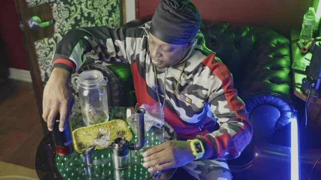 a black man disassembles an electronic water bong stir the unburned marijuana