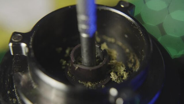close up of using a probe to pack marijuana into the bowl of a vaporizer used for smoking pot or medical marijuana