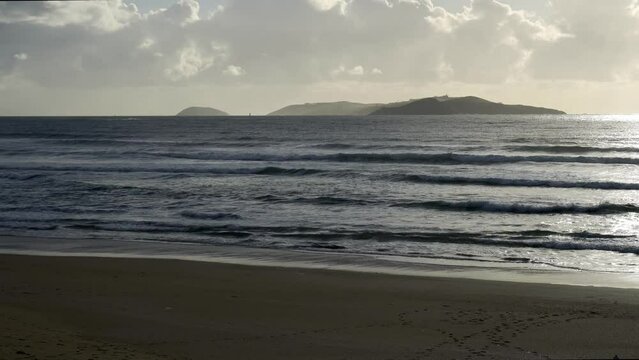 Ons Islands seen from the empty beach of La Lanzada in Galicia. Atlantic Ocean with waves and fine sand.