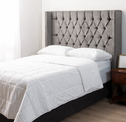 Modern Bedroom Elegance: Gray Tufted Headboard Enhances Dark Upholstered Bed with Wooden Nightstand and White Bedding, Creating a Serene Ambiance.