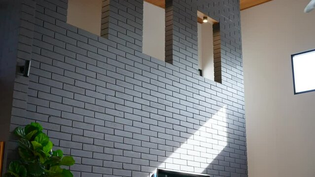 Grey brick feature wall with window cutouts. High ceiling modern home with wooden ceiling interior of house