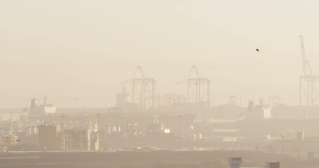 A hazy view of a port with cranes and ships, with copy space