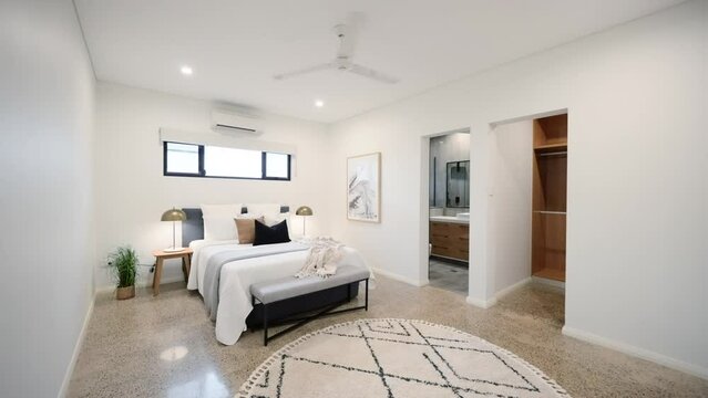 Large modern main bedroom with ensuite walk-in robe polished concrete floor and interior designed furniture decor in home house.