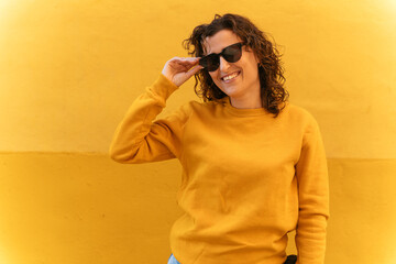 Positive woman in sunglasses near wall - 712932927
