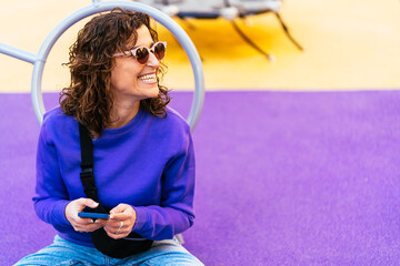 Cheerful woman browsing smartphone on playground