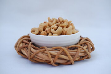 Roasted cashew nuts in white bowl on bamboo mat, stock photo