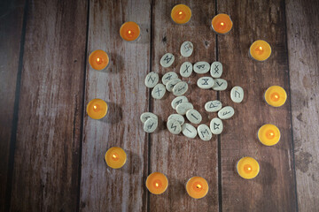 top view of lighted candles in a circle with stone runes in the center on a wooden table