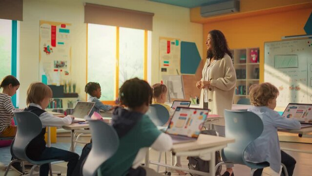 Class of Young Multiethnic Children Using Laptop Computers while Studying Math and Geometry in Grade School. Happy Female Teacher Explains Shapes and Measurements to Smart Boys and Girls