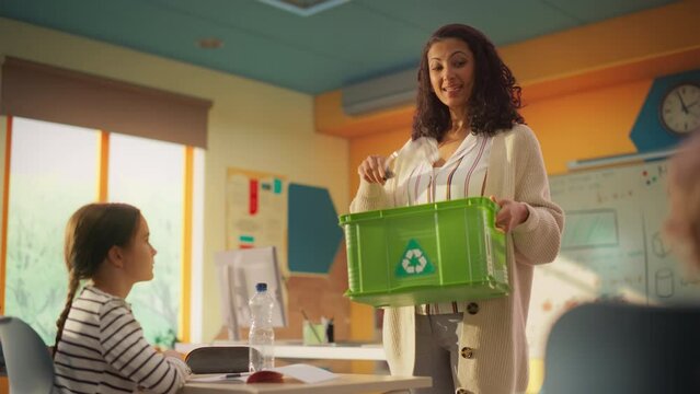 Curious Attentive Primary School Kids Listening to a Lecture About Recycling. Female Teacher Showing a Plastic Bottle as an Example and Putting the Waste in a Dedicated Bin.