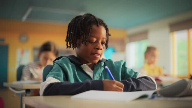 Talented Small African American Boy Asking Teacher a Question in Class. Portrait of a Happy Elementary School Student Studying Hard, Learning New Things, Getting Modern Education with Other Kids