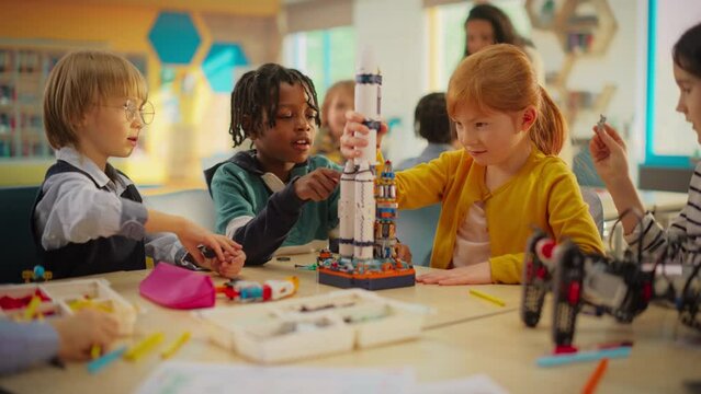 Elementary School Students Sitting Behind a Table in a Group, Building a Space Rocket Model for a Science and Technology Fair. Young Boys and Girls Wish to Become Engineers and Space Explorers
