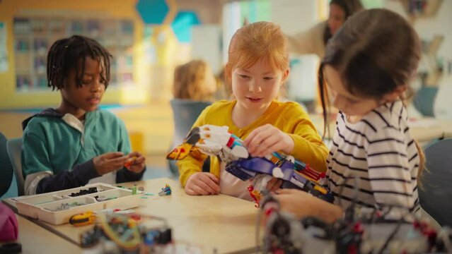Diverse Primary School Kids Building a Mechanical Hand with Hydraulic Power. Girls are Testing the Functionality of the Project in Class. Young Engineering Team Create an Innovative Invention