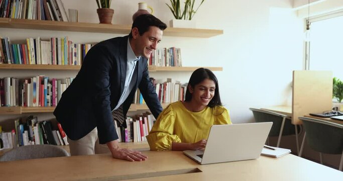 Indian female employee ask male mentor about corporate program, working on joint on-line task. Hispanic man explains to colleague new project, share ideas, solutions met together in coworking office