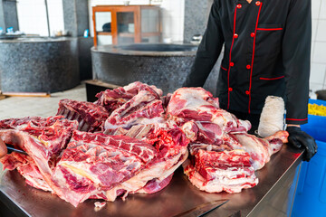 Butchering was done by a butcher cook in a restaurant. man in uniform touching fresh meat on stall...