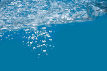 Bluewater waves on the surface ripples blurred. Defocus blurred transparent blue colored clear calm water surface texture with splash and bubbles. Water waves with shining pattern texture background.