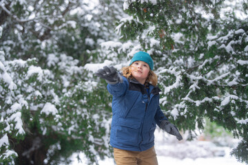 Fototapeta na wymiar Kid with snowball in snow. Winter holiday kids, snowball snowball activity. Child enjoy Christmas vacation. Kid in winter clothes in snowy forest. Trees covered white snow. Kid have fun playing snow