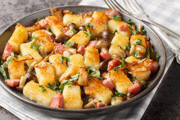 Homemade traditional Polish potato dumplings kopytka served with bacon, onions and mushrooms close-up in a plate on the table. Horizontal