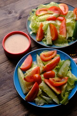 fresh raw vegetable salad. iceberg lettuce, sliced tomatoes, sliced cucumber and cherry tomatoes with peanut sauce salad dressing.