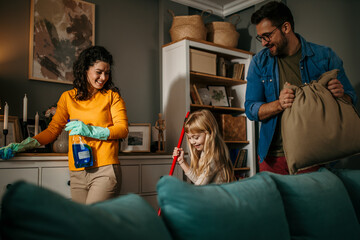 Mom, dad, and daughter engaged in a cleaning session, sharing smiles