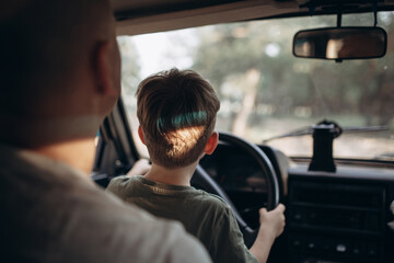 Dad teaches his son to drive a car view from the back