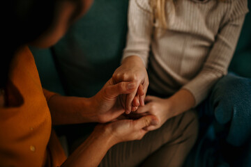Loving mother listening to a daughter with empathy and understanding while sitting together on sofa...