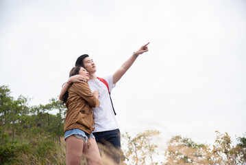 Young Asian tourists couple enjoying and exploring the forest or woods and bonding with love and romance. woman and man looking at the views outdoors together. Happy relationship lifestyle.