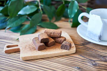 Chocolate truffles on a wooden board with a cup of tea