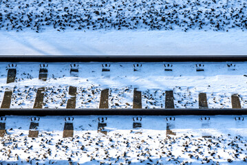 Frosted railway track seen from above. Two parallel steel rails, thresholds, screws covered with...